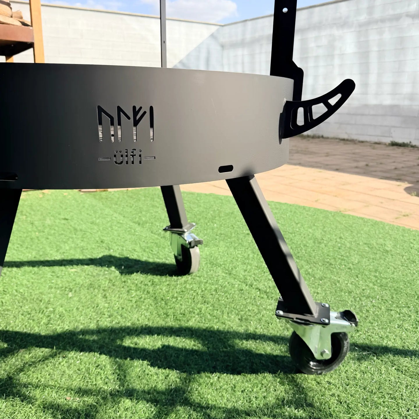 Table de soudure sur mesure en métal noir avec roulettes pivotantes sur gazon synthétique.