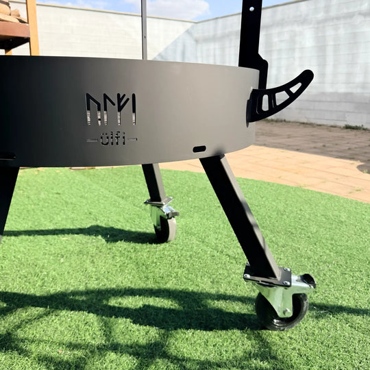 Table de soudure sur mesure en métal noir avec roulettes pivotantes sur gazon synthétique.