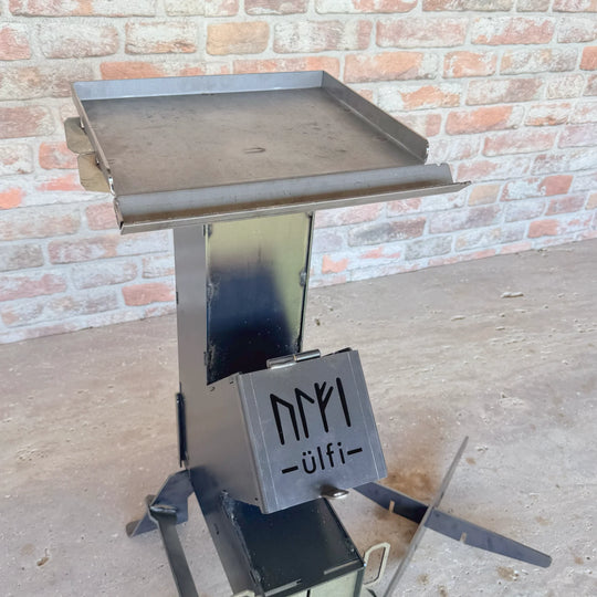 Barbecue de camping en métal avec plateau de cuisson et porte-accessoires.